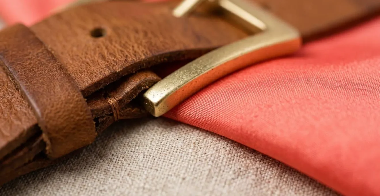 Close-up of neutral leather accessories against vibrant fabric texture